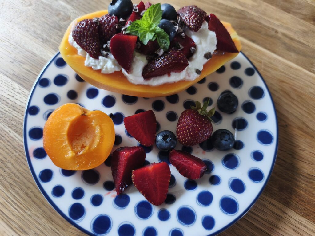halbe Papaya gefüllt mit Skyr und verschiedenen Beeren verziert